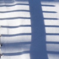 Shadows | Nearly covered by the snow, a pickett fence casts a long shadow in the afternoon light. (Herald / Tim Calabro)
